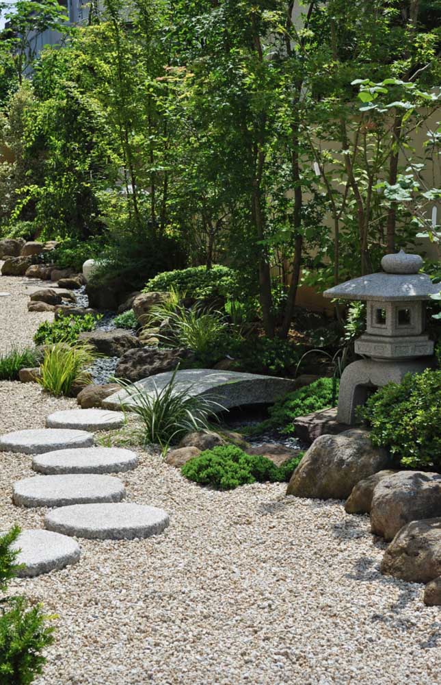 Grand jardin zen avec chemin en pierre, statues et mini pont 