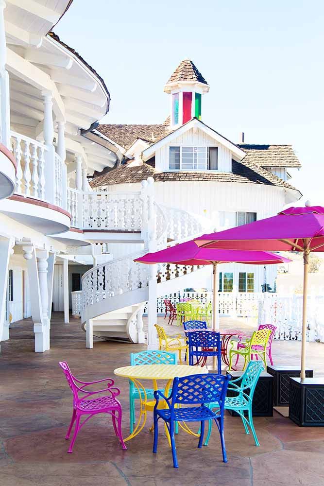 La façade de la maison toute blanche a gagné des parapluies, des tables et des chaises de couleurs intenses et contrastées