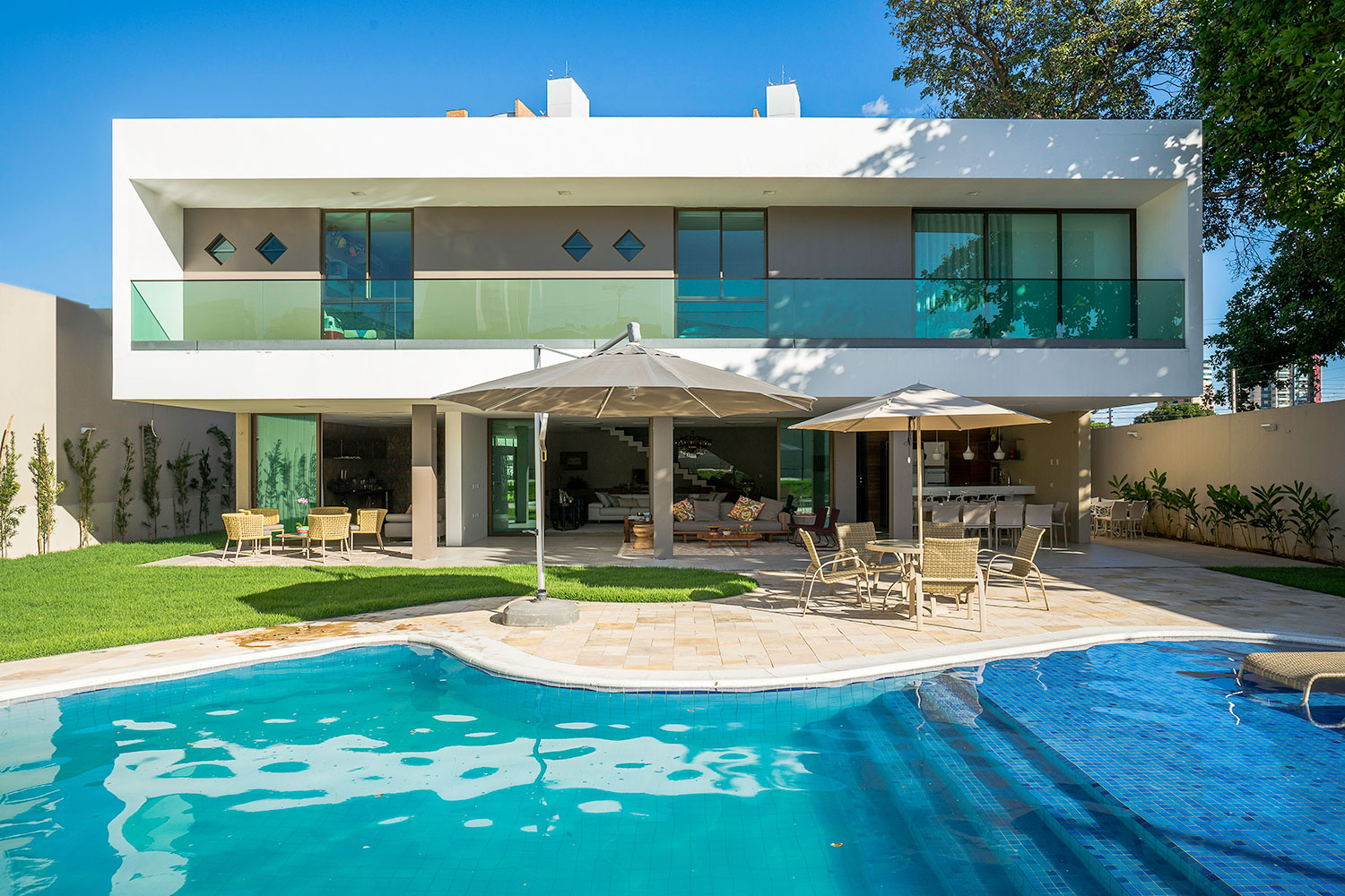 Modèle de maison avec garde-corps en verre et piscine à l'arrière