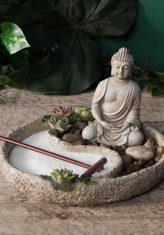 Jardin zen miniature avec une petite statue de Bouddha, des plantes succulentes et l'espace réservé au sable et au râteau; remarquez que le récipient en pierre où le jardin a été construit forme le symbole sacré de Tao